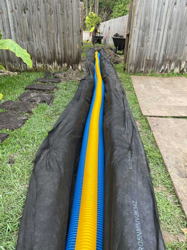 Geo fabric with blue and yellow corrugated pipe in trench
