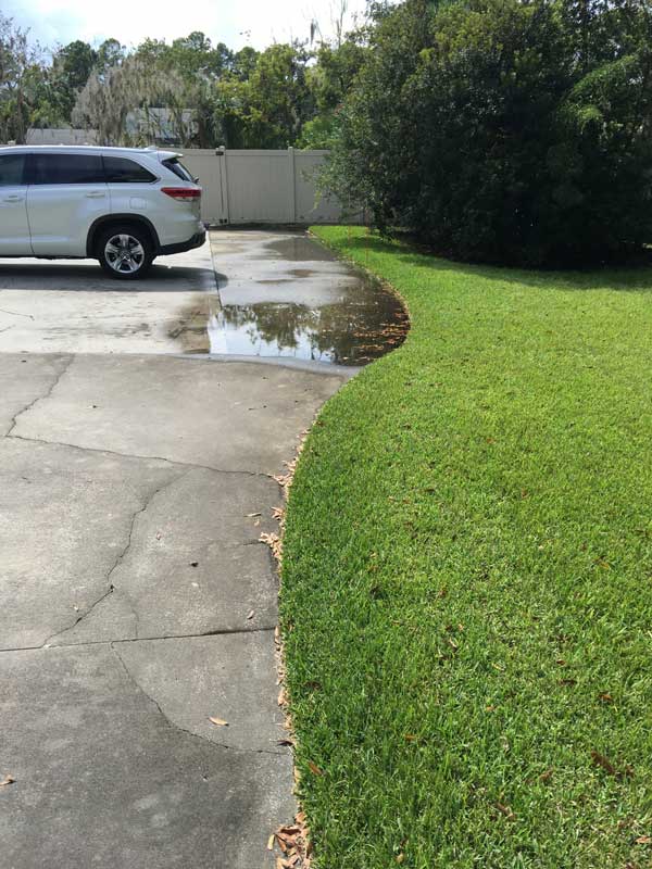 Standing water pooling on a driveway before drainage work